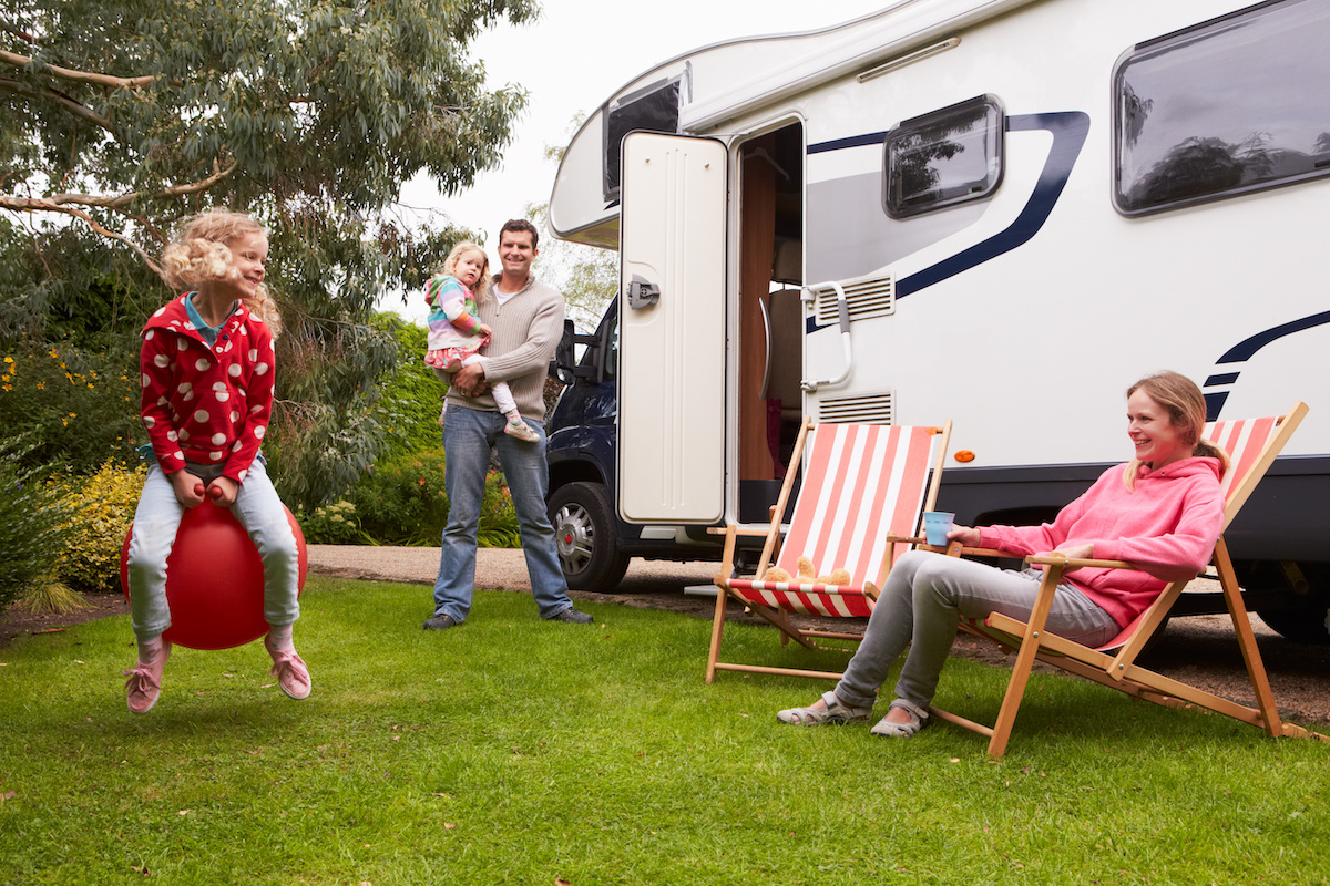 Family of four outside of their RV enjoying the outdoors. 